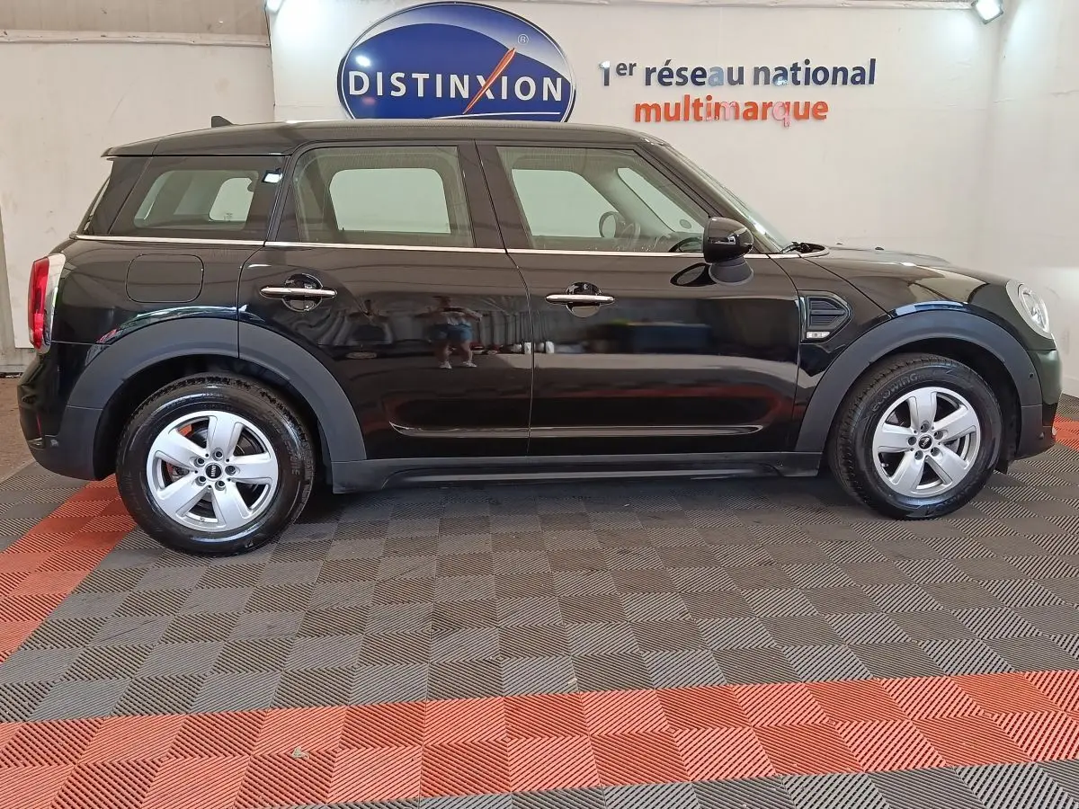 Vue latérale droite d'une MINI Countryman noire de 2019, avec jantes argentées et toit noir dans un showroom.