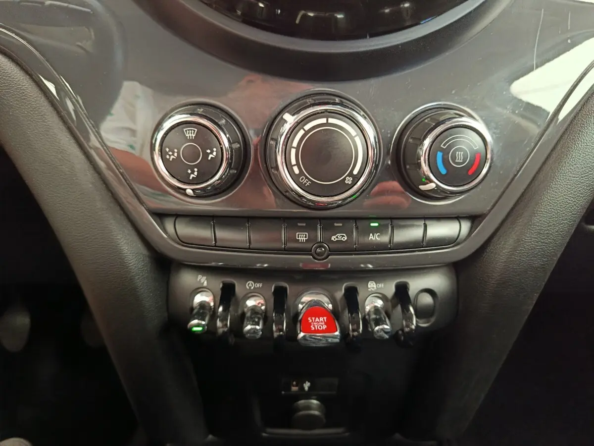 Vue rapprochée de la console centrale noire du MINI Countryman 2019 avec commandes de climatisation et bouton start/stop rouge.