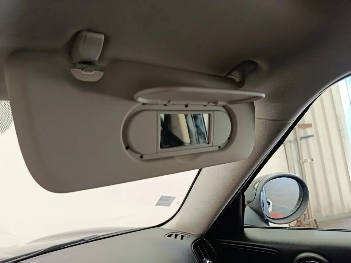 Détail du pare-soleil avec miroir intégré côté conducteur dans une MINI Countryman noire, vue intérieure avant droite.