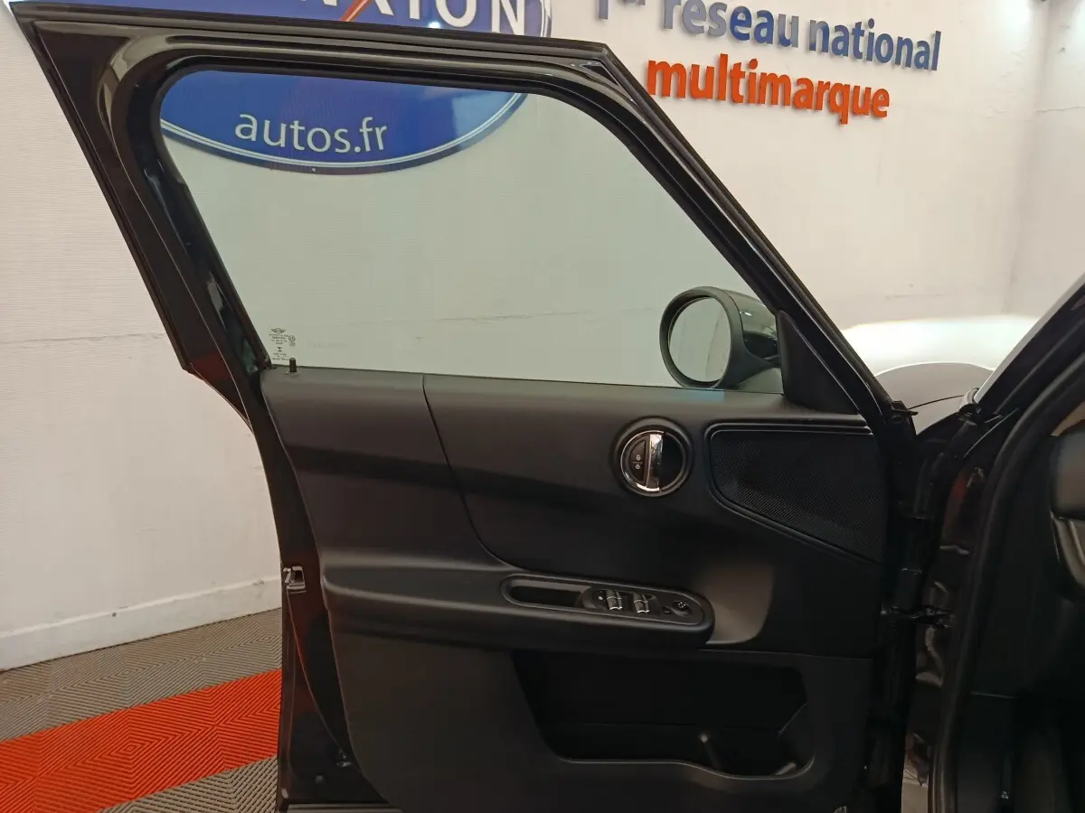 Vue rapprochée de la porte avant gauche noire ouverte d’une MINI Countryman 2019, montrant les commandes de vitres et le rétroviseur.