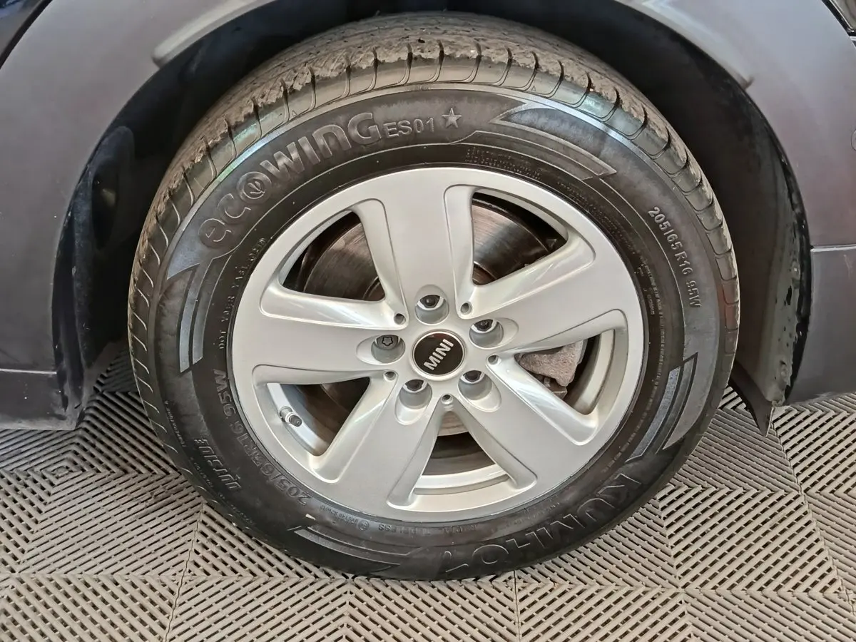 Gros plan sur la roue avant droite d'une MINI Countryman noire, mettant en valeur la jante argentée et le pneu Kumho.