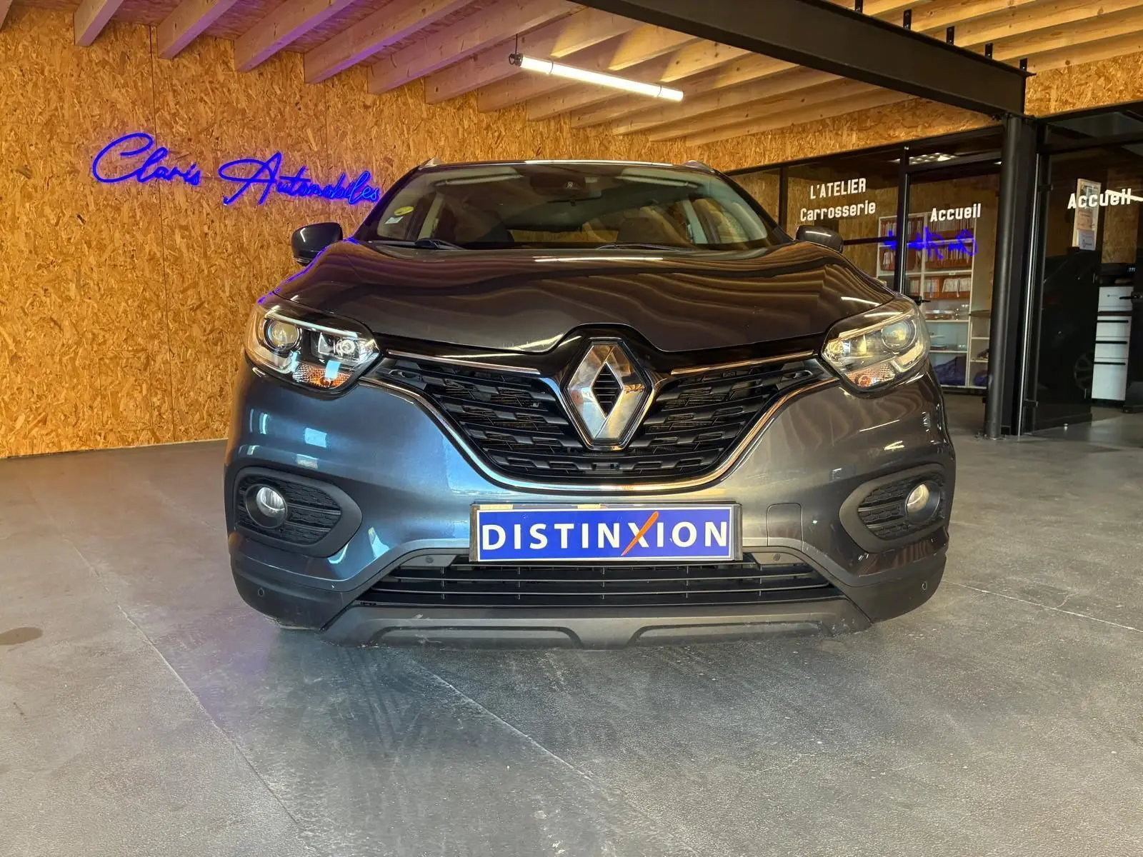 Vue frontale d'un Renault Kadjar gris 2019 avec calandre noire et logo chromé, en intérieur showroom.