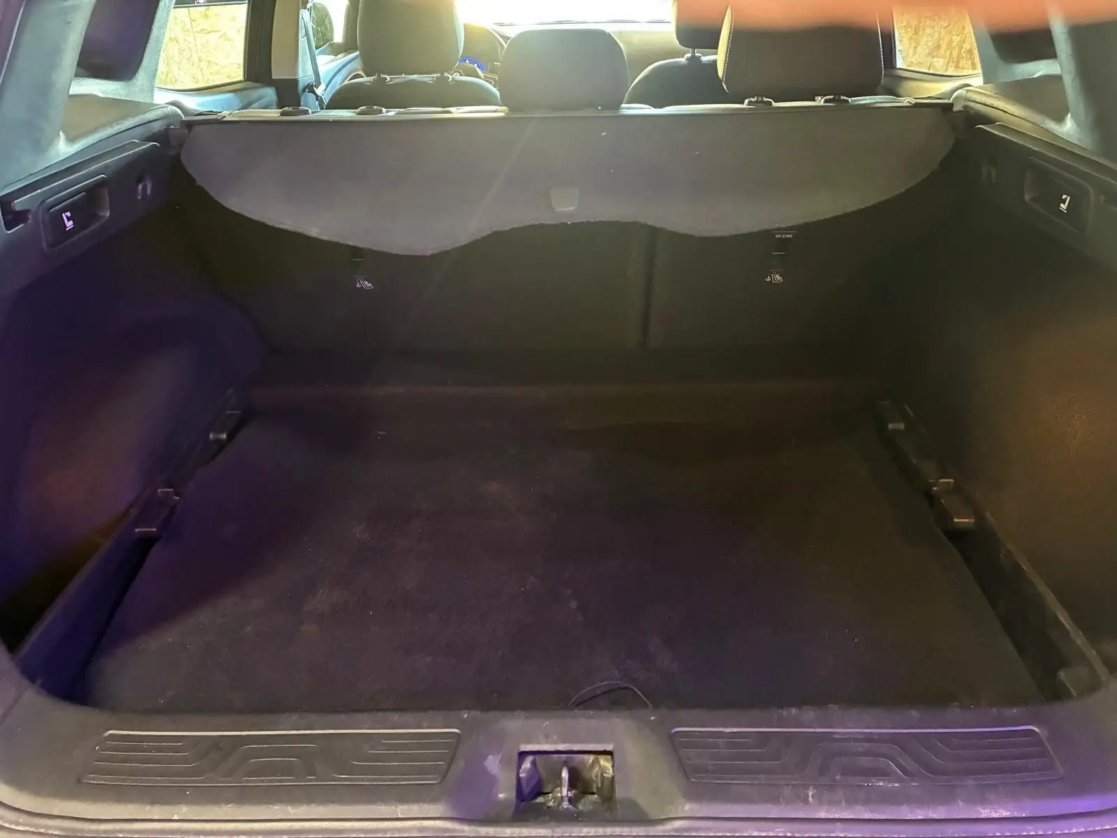 Vue intérieure du coffre spacieux et noir du Renault Kadjar gris, avec banquette arrière visible en arrière-plan.