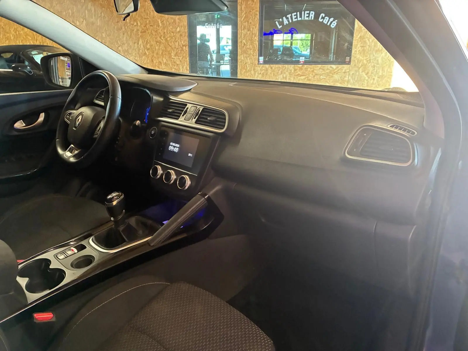 Vue intérieure côté conducteur du Renault Kadjar gris 2019, montrant le tableau de bord et la console centrale avec boîte manuelle.