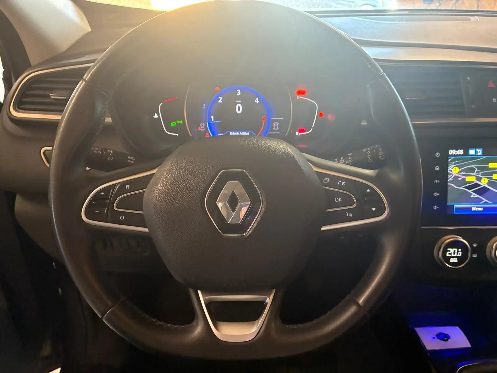 Vue rapprochée du volant noir et du tableau de bord digital du Renault Kadjar gris de 2019 avec écran GPS allumé.