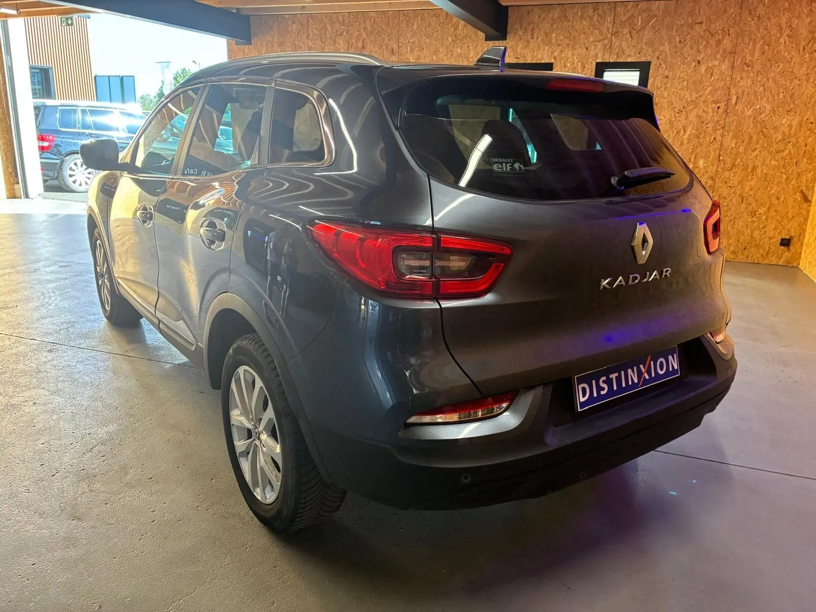 Vue 3/4 arrière droite d'un Renault Kadjar gris 2019 dans un garage avec éclairage naturel et artificiel.