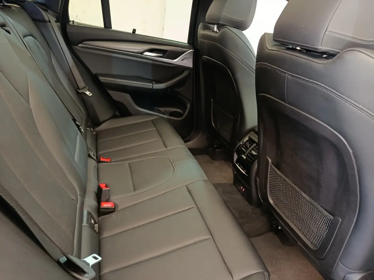 Vue intérieure arrière côté droit du BMW X3 xDrive30e 2023, sièges en cuir noir avec accoudoirs et aérateurs centraux.