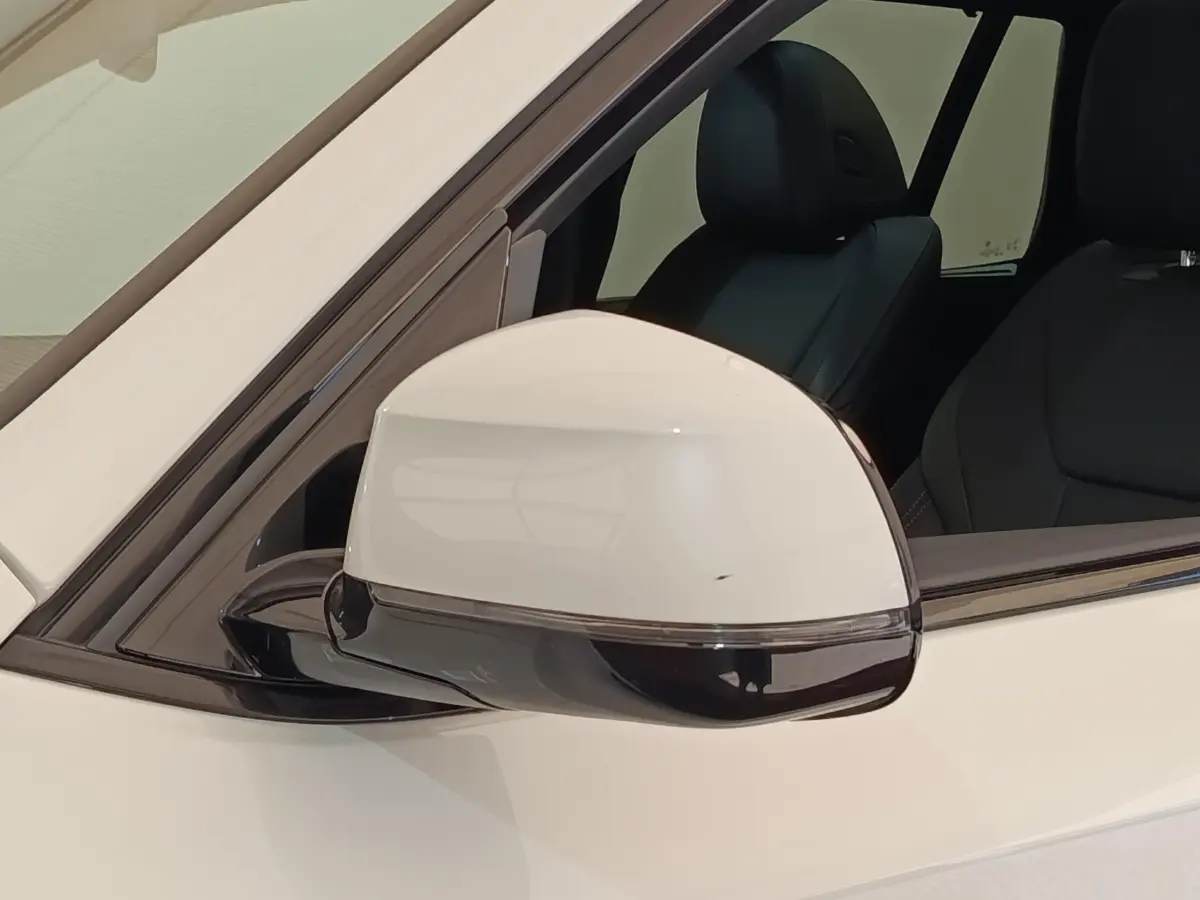 Gros plan sur le rétroviseur droit blanc du BMW X3 xDrive30e 2023 avec intérieur noir visible en arrière-plan.