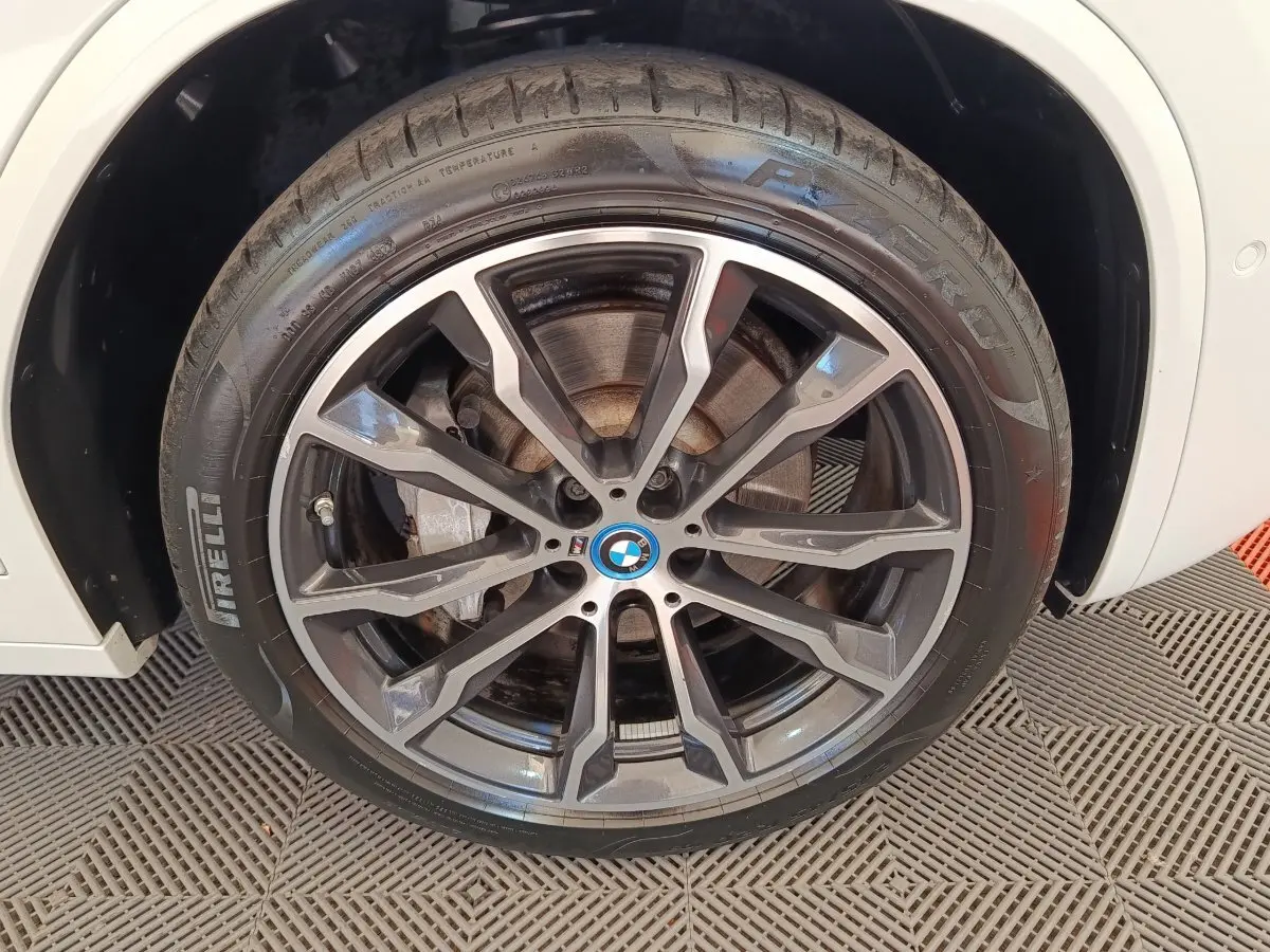 Gros plan sur la roue avant gauche blanche BMW X3 xDrive30e avec jante alliage noire et logo BMW central.