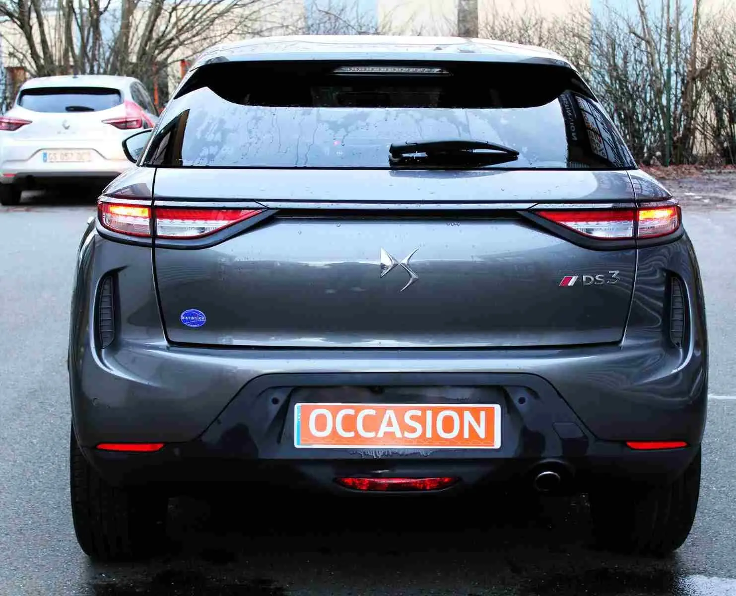 Vue arrière d'un DS3 Crossback gris platinium métal avec feux allumés et plaque d'occasion visible.
