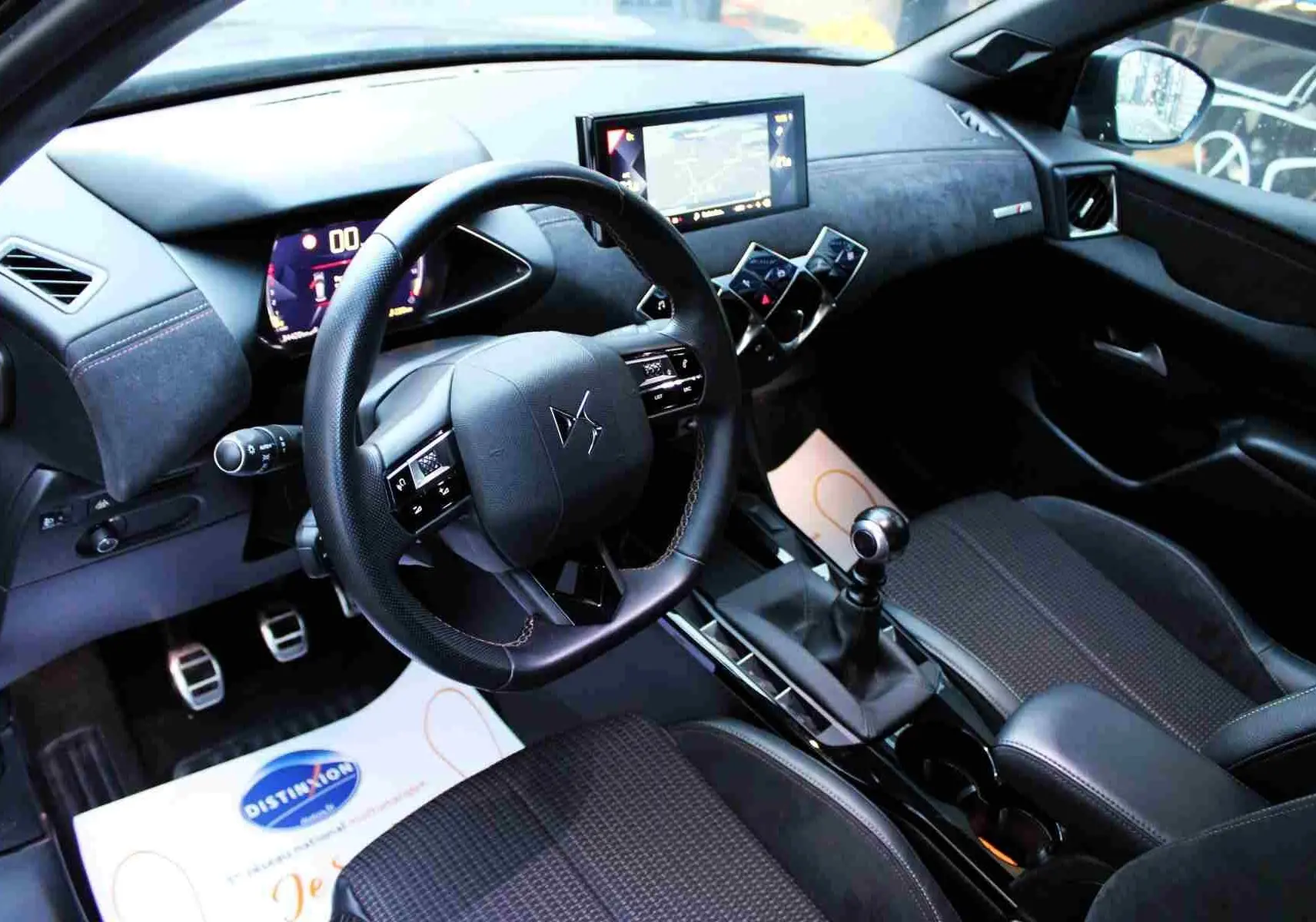 Vue intérieure côté conducteur du DS3 Crossback 2021, tableau de bord noir avec volant cuir et levier de vitesse manuel.
