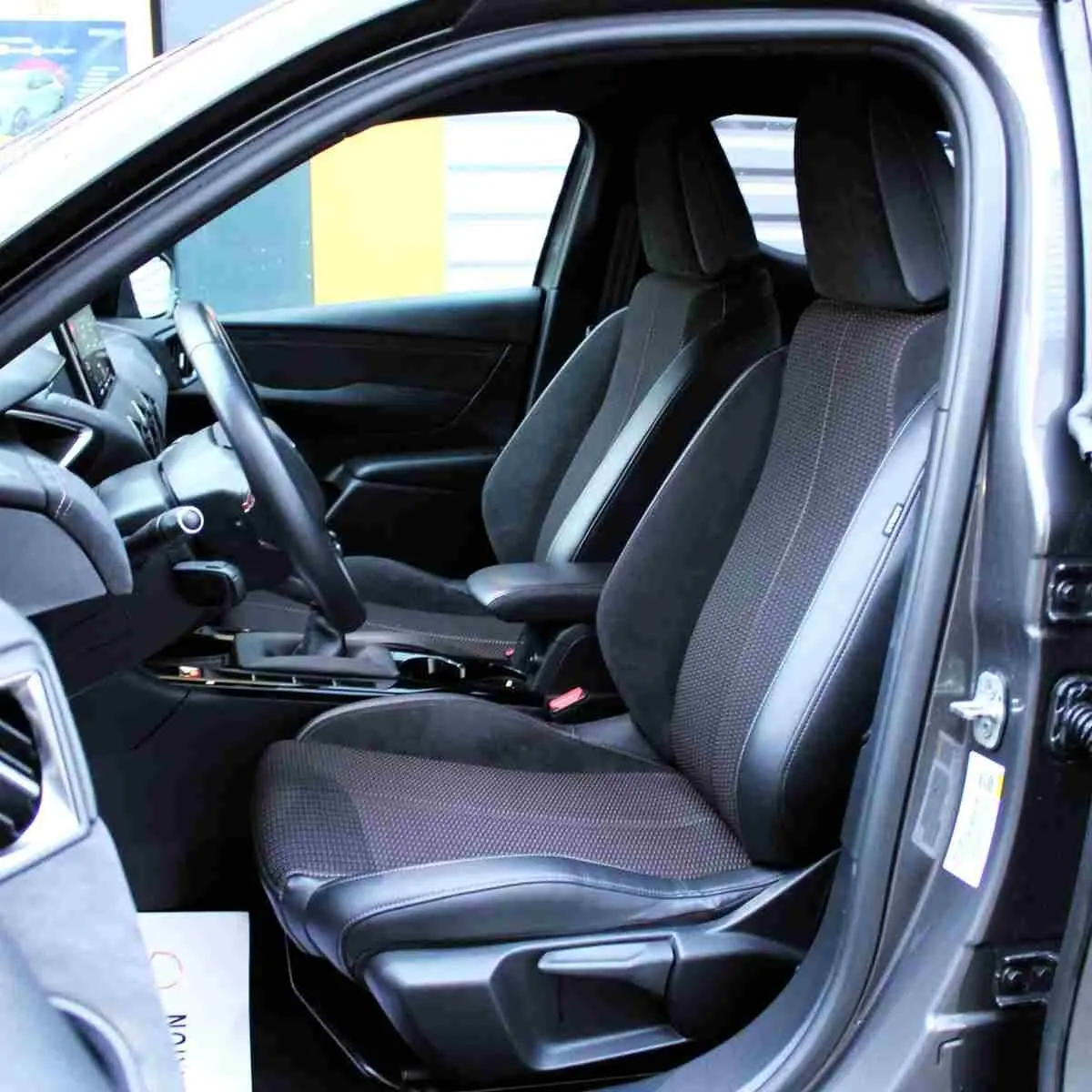 Vue intérieure côté conducteur du DS3 Crossback gris platinium, mettant en valeur les sièges tissu et cuir noir.