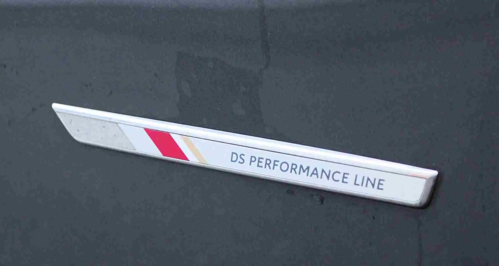 Gros plan sur l’insigne latéral "DS Performance Line" sur la carrosserie gris platinium métallisé du DS3 Crossback.
