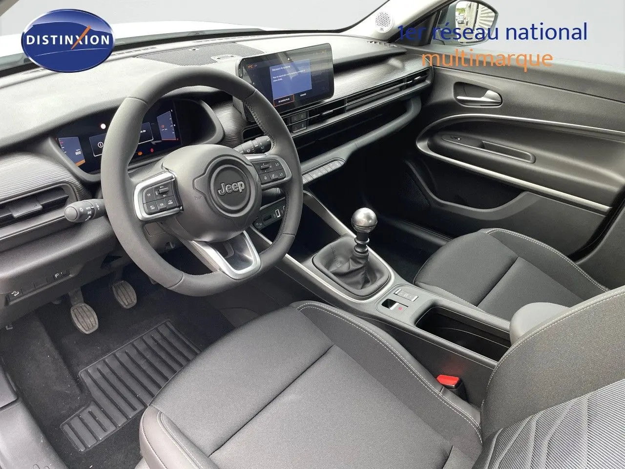 Intérieur noir du Jeep Avenger 2024, vue côté conducteur montrant volant, tableau de bord digital et levier de vitesse manuel.