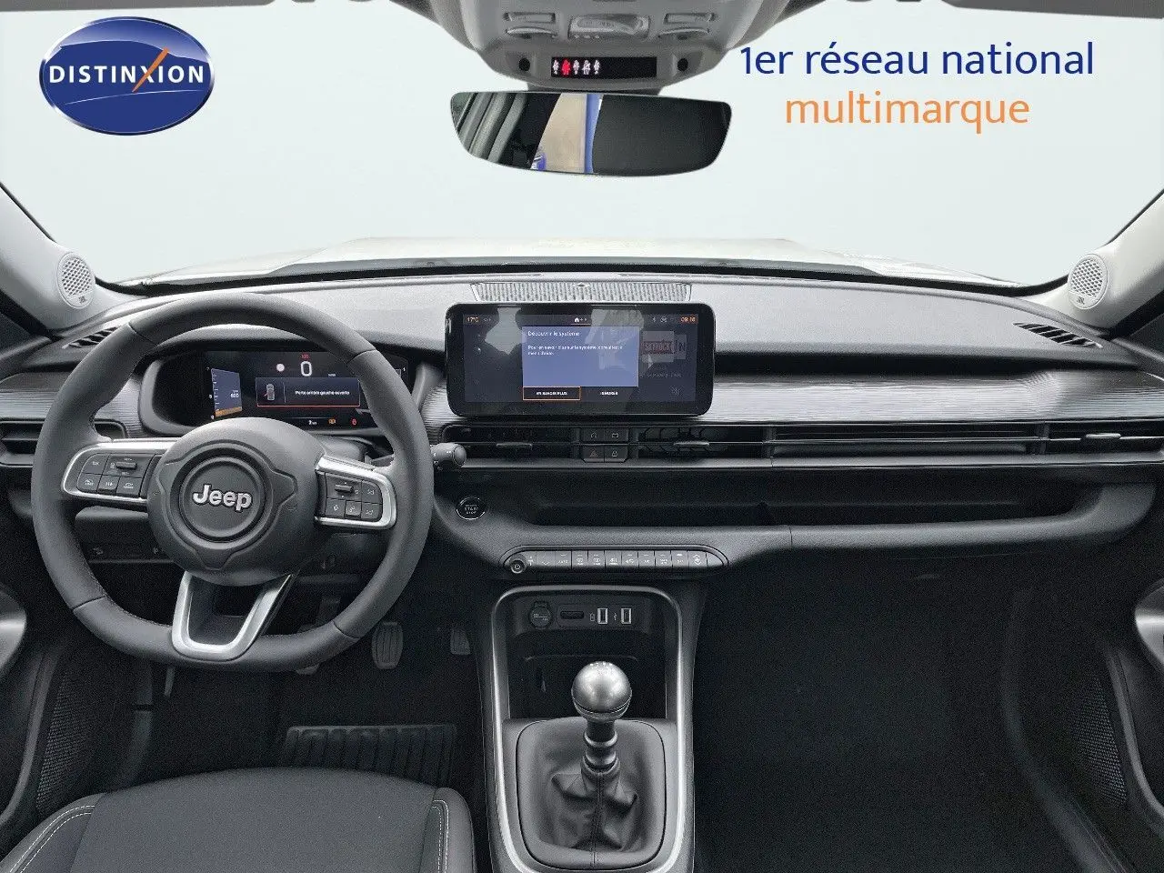 Intérieur du Jeep Avenger 2024 vue de face, tableau de bord noir avec écran tactile et levier de vitesse manuel.