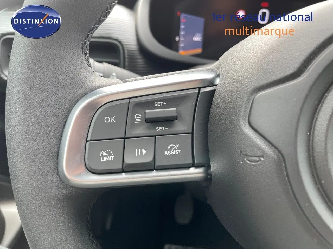 Gros plan sur les commandes au volant à gauche d'un Jeep Avenger blanc neige 2024, avec boutons de régulateur et assistances.