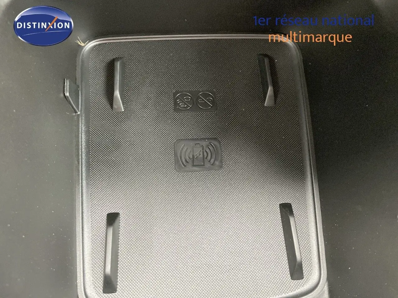 Surface de recharge sans fil noire dans l'habitacle du Jeep Avenger blanc neige, vue en plongée.