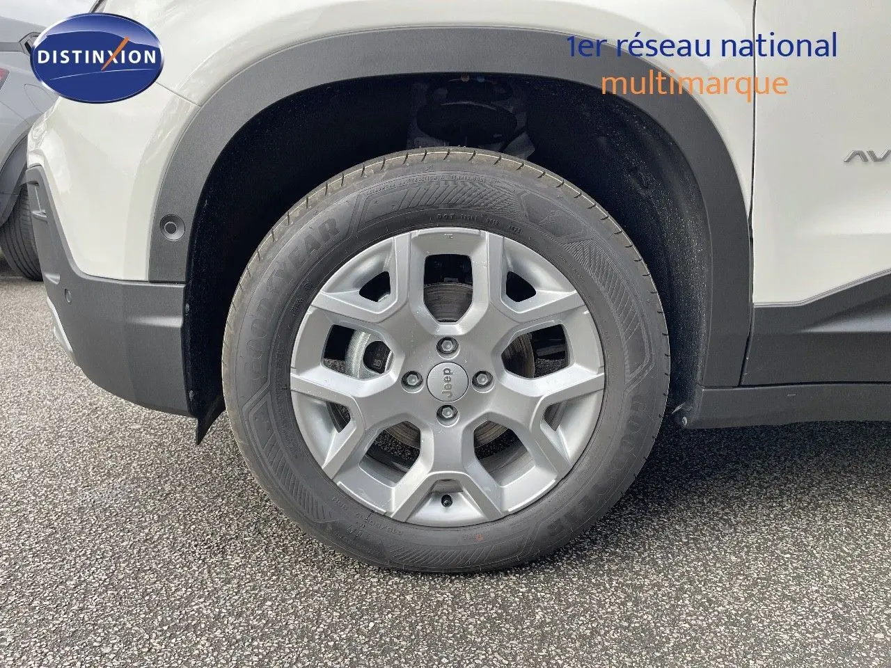 Gros plan sur la roue avant gauche d’un Jeep Avenger blanc neige avec jante alliage et pneus Goodyear.