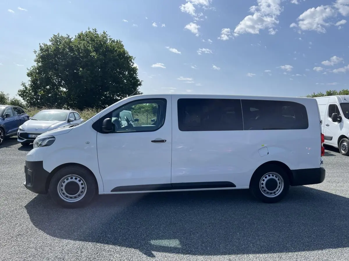 Profil côté gauche d'un Toyota Proace Fourgon blanc 2021 avec portes vitrées et jantes acier 16 pouces.