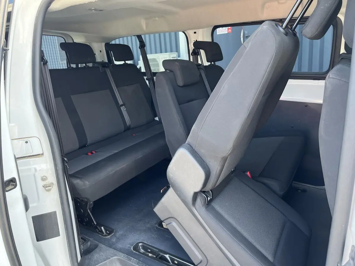 Vue intérieure côté droit du Toyota Proace Fourgon blanc 2021, montrant les sièges en tissu gris clair et la porte latérale ouverte.