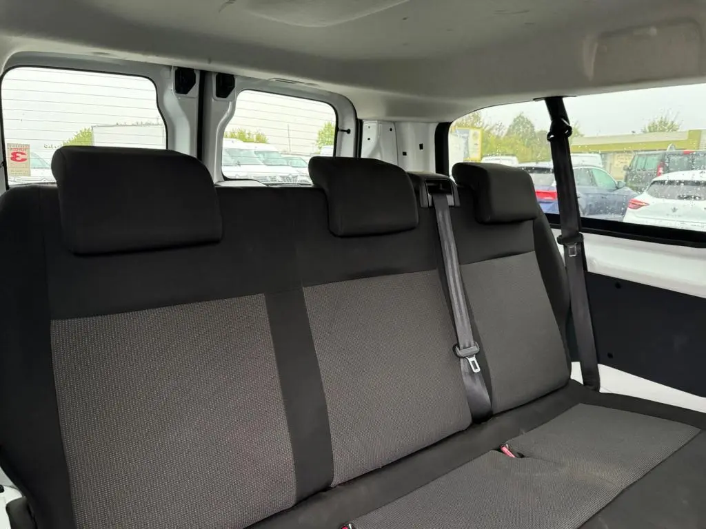 Vue intérieure sur la banquette arrière en tissu gris clair du Toyota Proace Fourgon blanc, avec ceinture et fenêtres latérales visibles.