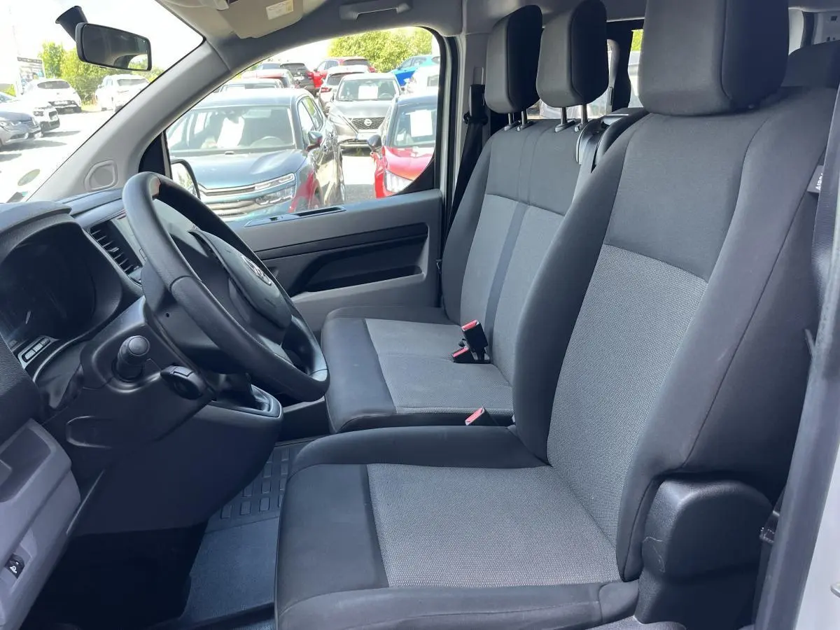Vue intérieure côté conducteur du Toyota Proace Fourgon 2021, sièges tissu gris clair et tableau de bord noir.