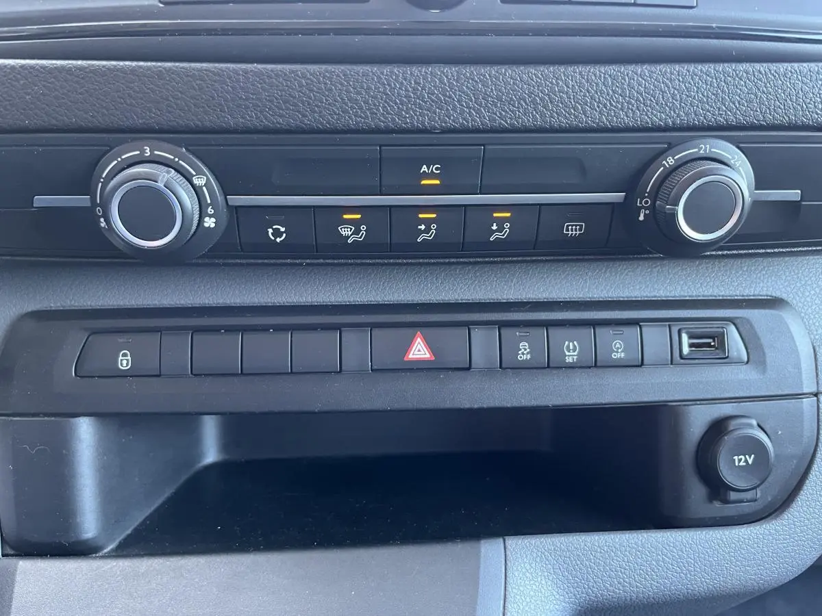 Tableau de bord noir du Toyota Proace Fourgon 2021 avec commandes climatisation et prise 12V visibles en gros plan.