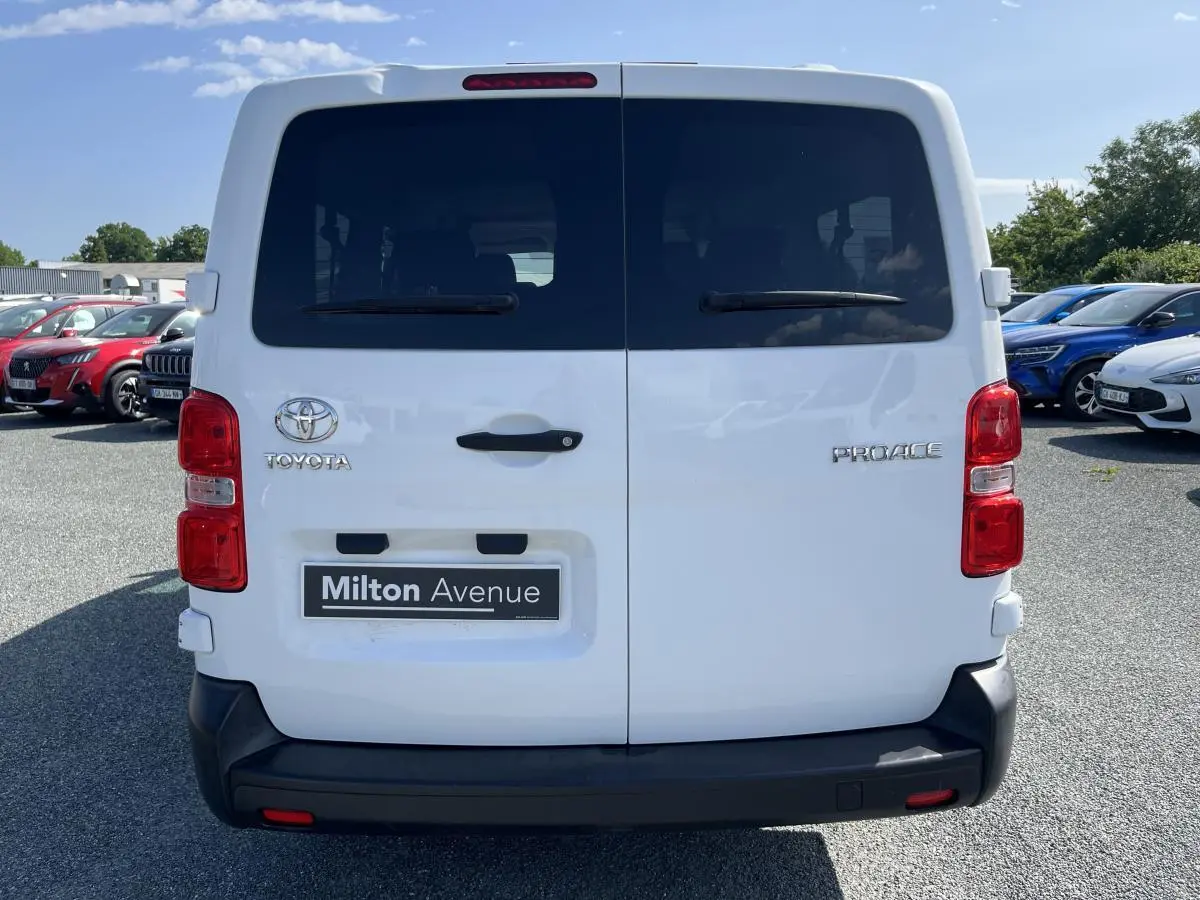 Vue arrière d'un Toyota Proace Fourgon blanc avec portes battantes vitrées et pare-chocs noir en plastique.