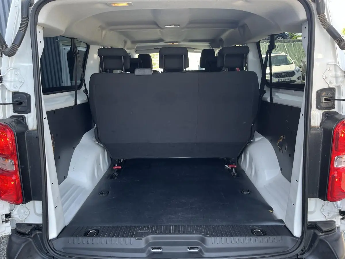 Vue arrière ouverte du Toyota Proace Fourgon blanc 2021, montrant l'espace de chargement et la banquette arrière noire.