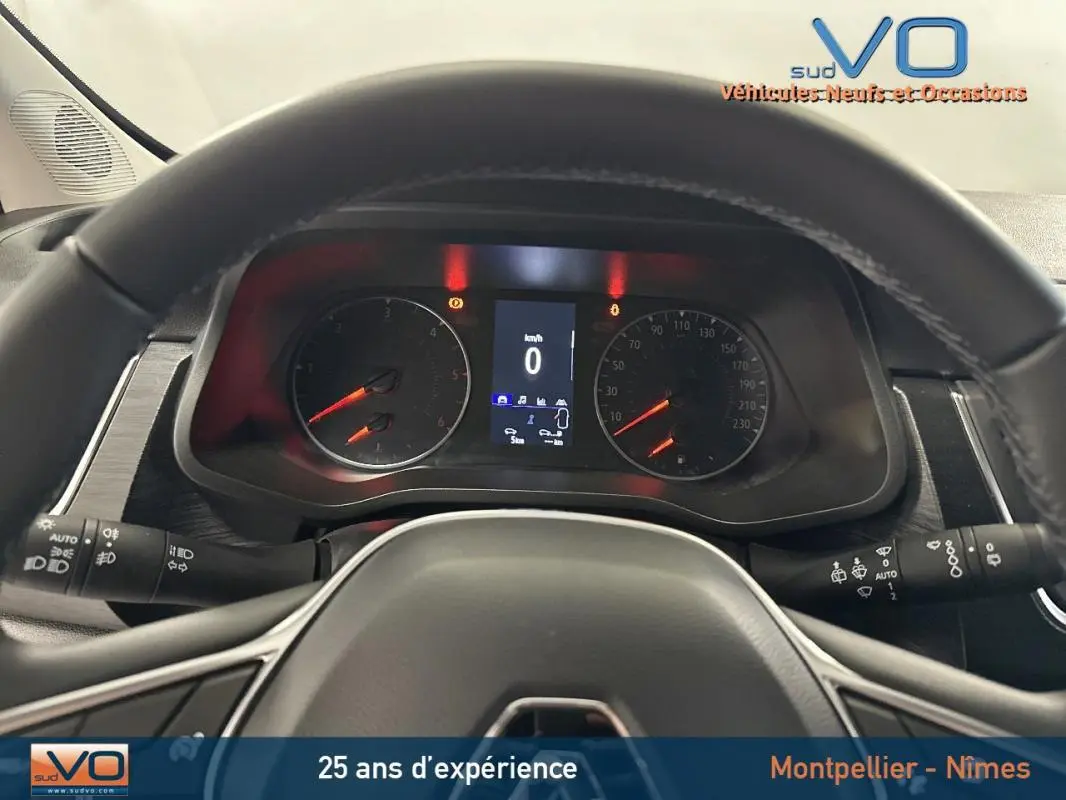 Vue intérieure du tableau de bord du Renault Trafic Fourgon gris 2025, avec volant et compteurs numériques allumés.