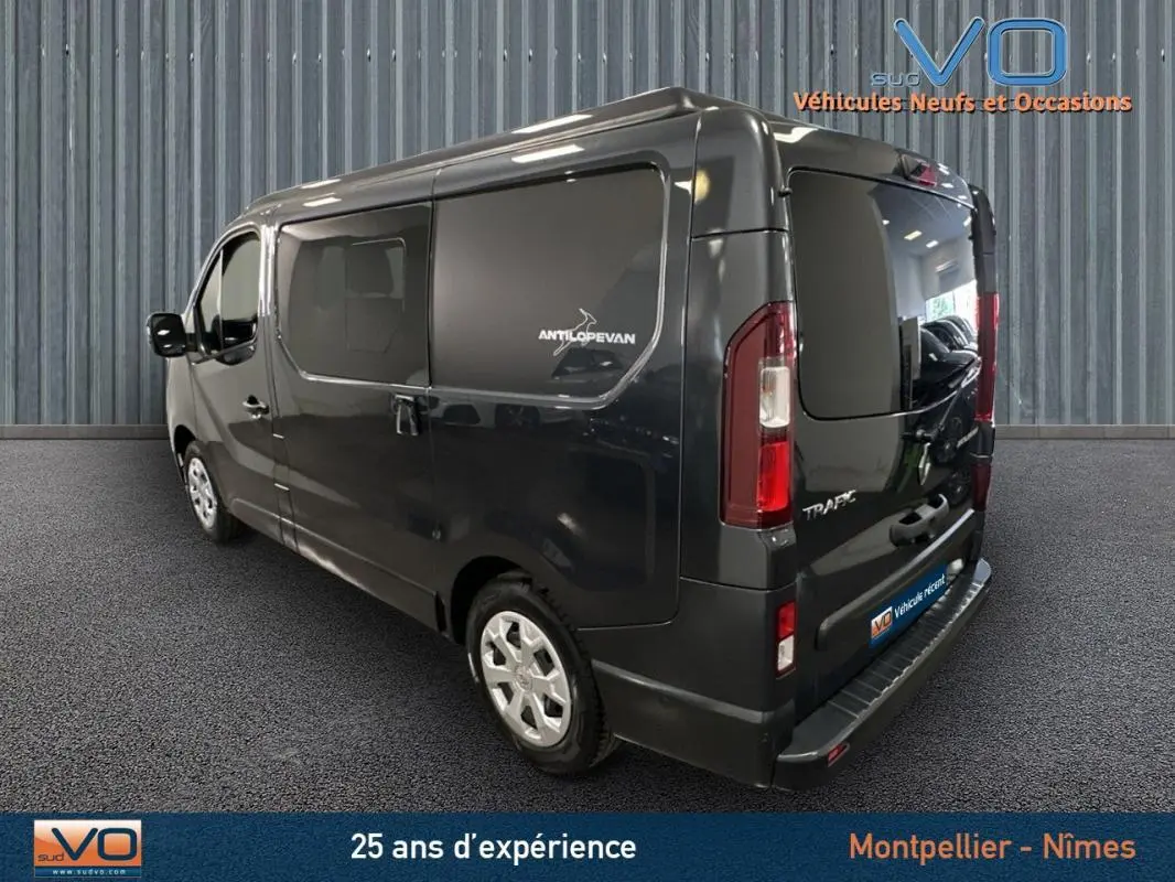 Vue 3/4 arrière droite du Renault Trafic Fourgon gris 2025 avec vitres surteintées et logo Antilopevan sur la porte latérale.
