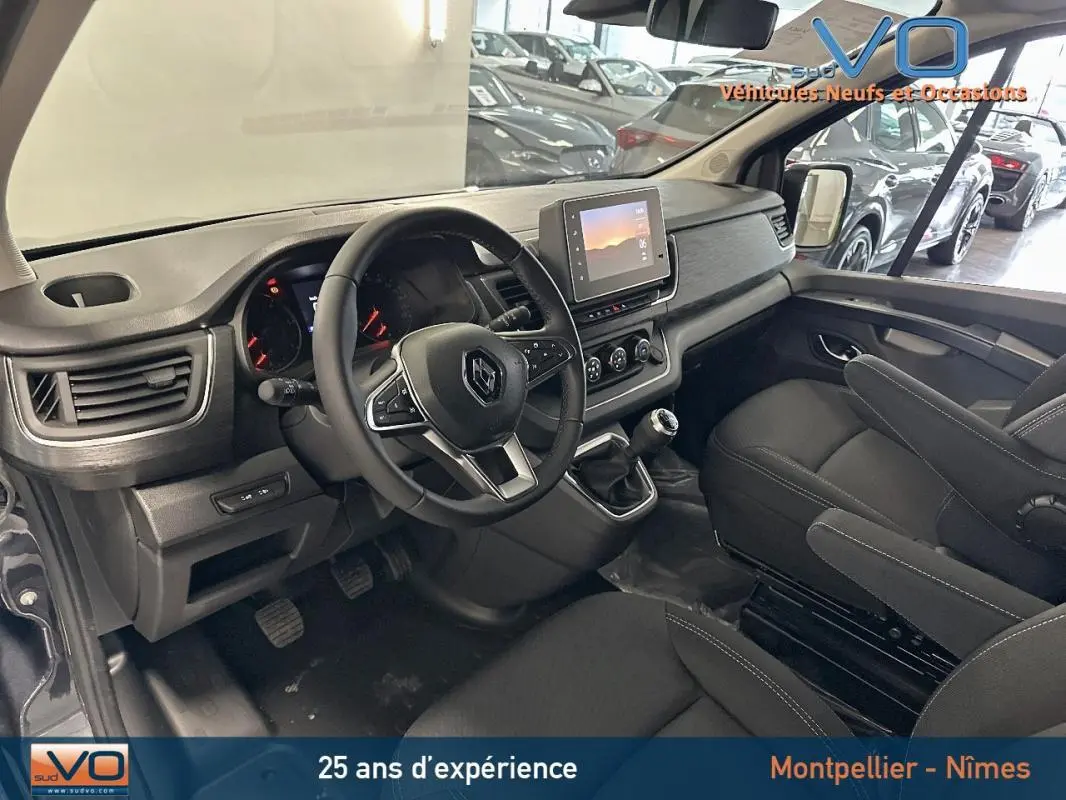 Intérieur du Renault Trafic Fourgon gris 2025, vue côté conducteur sur tableau de bord et sièges noirs.