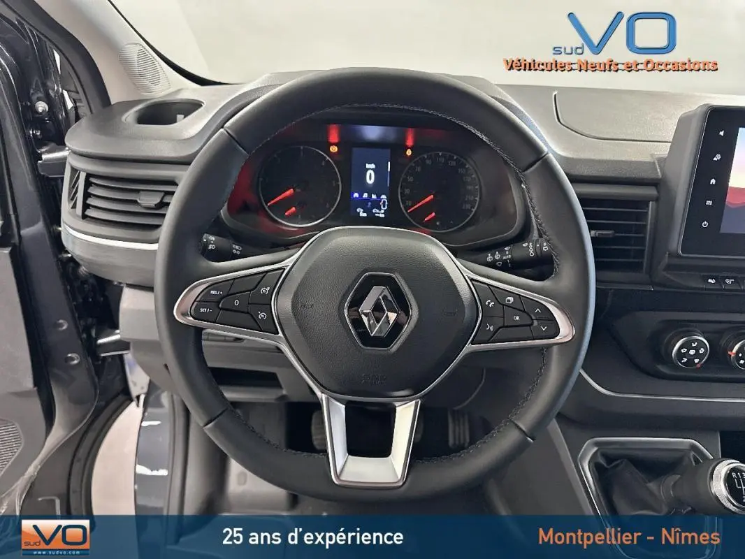 Vue intérieure centrée sur le volant noir du Renault Trafic Fourgon gris 2025 avec tableau de bord et commandes visibles.
