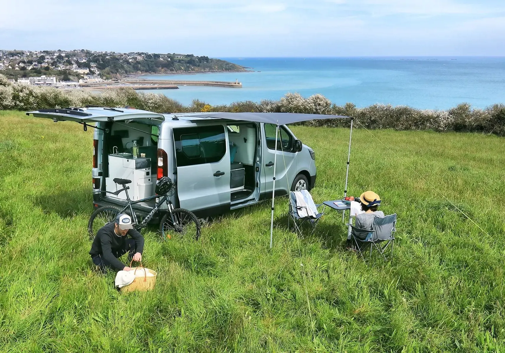 Renault Trafic Fourgon gris platine vu de côté droit arrière, porte coulissante ouverte et auvent déployé.