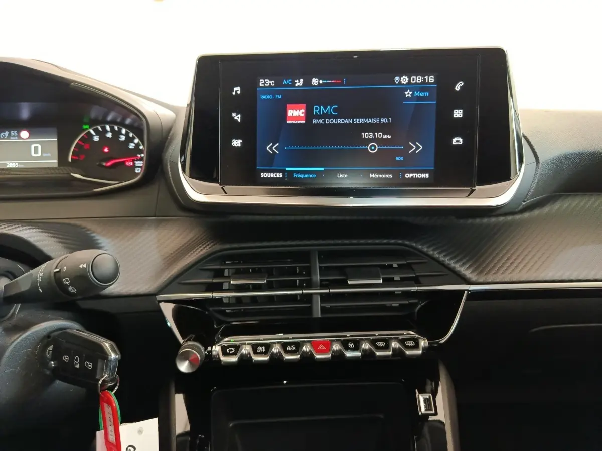 Tableau de bord de Peugeot 208 PureTech blanc, vue centrée sur l’écran tactile et les commandes en rangée.