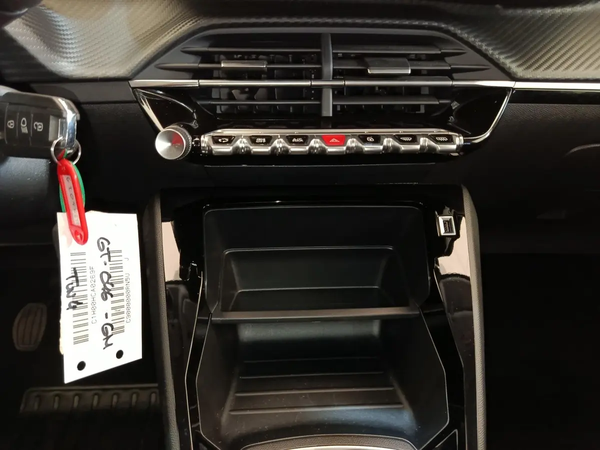 Vue rapprochée du tableau de bord noir de la Peugeot 208 2023 avec commandes et prise USB visible.