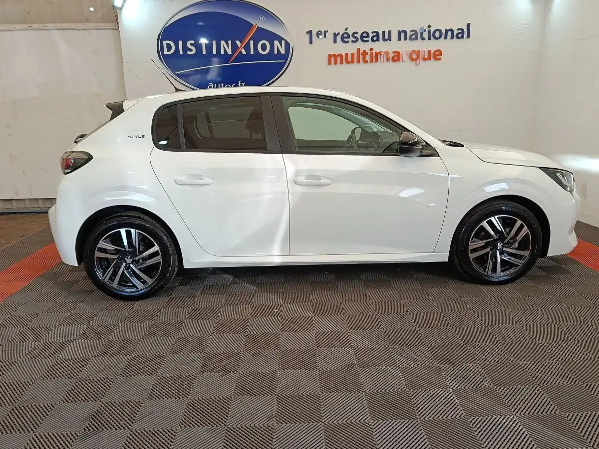 Profil droit d'une Peugeot 208 PureTech 75 S&S Style blanche, avec jantes alliage et vitres teintées.