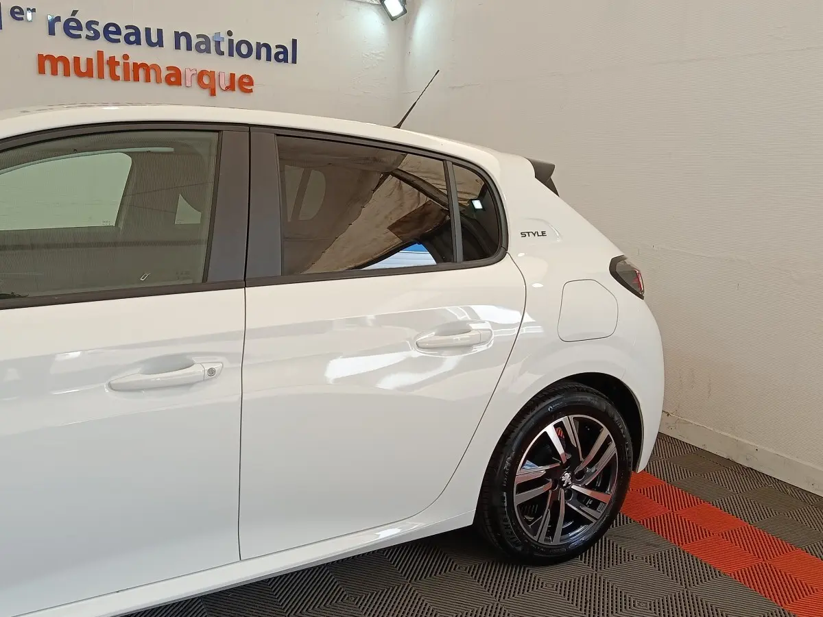 Vue latérale droite d'une Peugeot 208 PureTech 75 S&S Style blanche, avec jantes alliage et badge Style arrière.