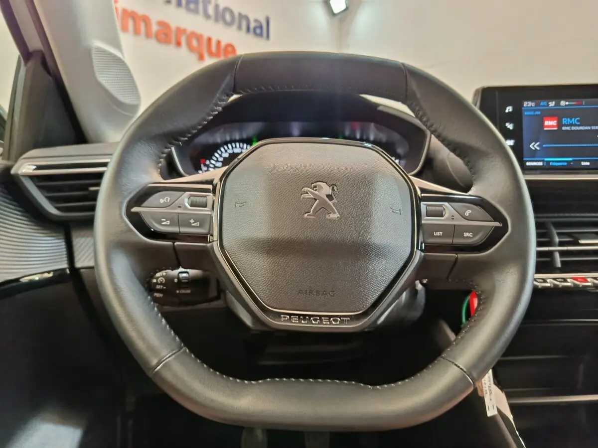 Vue rapprochée du volant cuir multifonctions de la Peugeot 208 PureTech 75 S&S Style avec tableau de bord numérique.