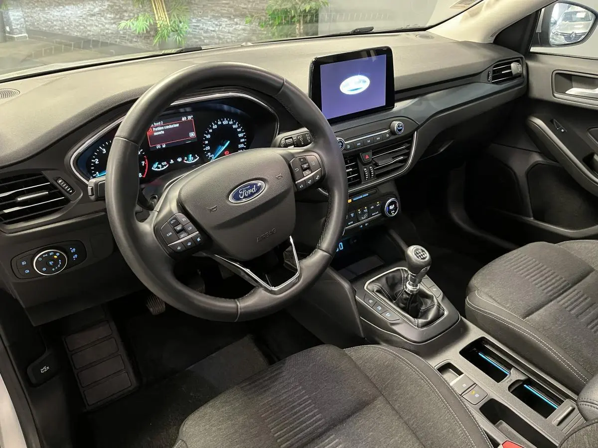 Intérieur avant droit de la Ford Focus gris, volant multifonction, écran tactile et boîte manuelle visible.