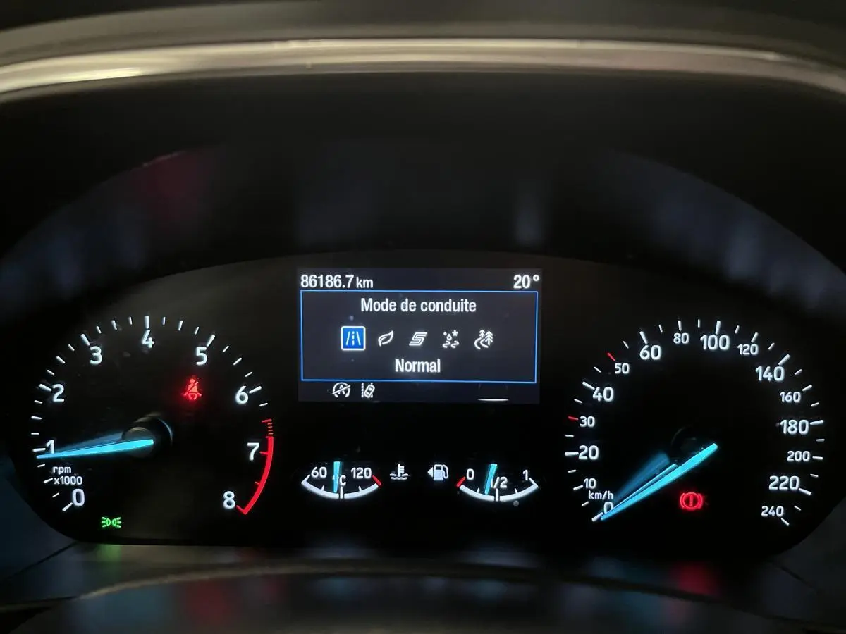 Tableau de bord de Ford Focus gris 2021 montrant l'affichage numérique du mode de conduite et compteurs éclairés.