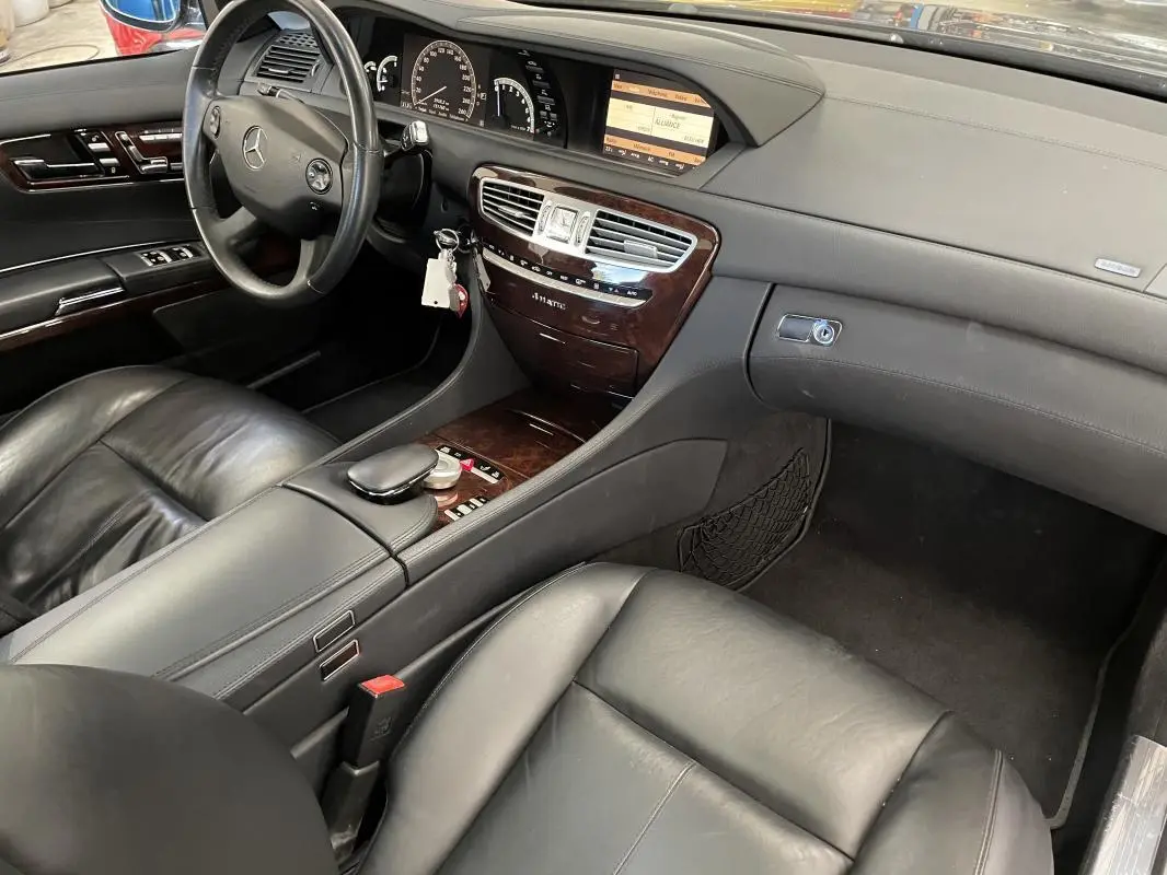 Vue intérieure côté conducteur de la Mercedes Classe CL 500 4-Matic 2009 avec cuir noir et console bois.