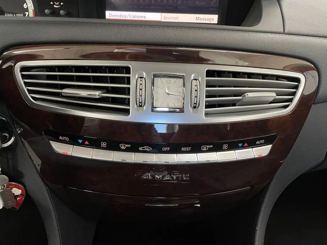 Plan rapproché du tableau de bord en bois foncé de la Mercedes Classe CL 500 4-Matic, avec horloge centrale et commandes climatisation.