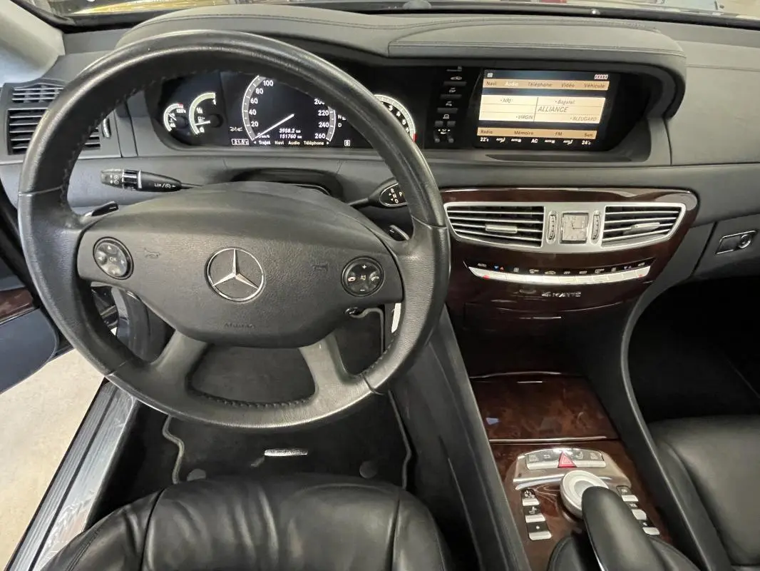 Vue intérieure du tableau de bord et volant multifonctions en cuir noir d'une Mercedes Classe CL 500 4-Matic de 2009.