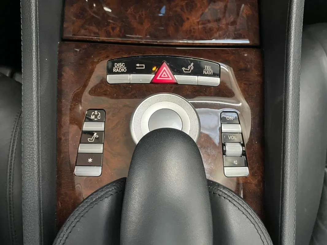 Vue rapprochée de la console centrale en bois foncé avec commandes multimédia et levier de vitesse cuir noir d'une Mercedes Classe CL 500 4-Matic.