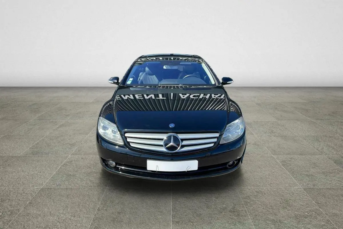 Vue frontale d'une Mercedes Classe CL 500 4-Matic noire avec calandre chromée et phares bi-xénon allumés.