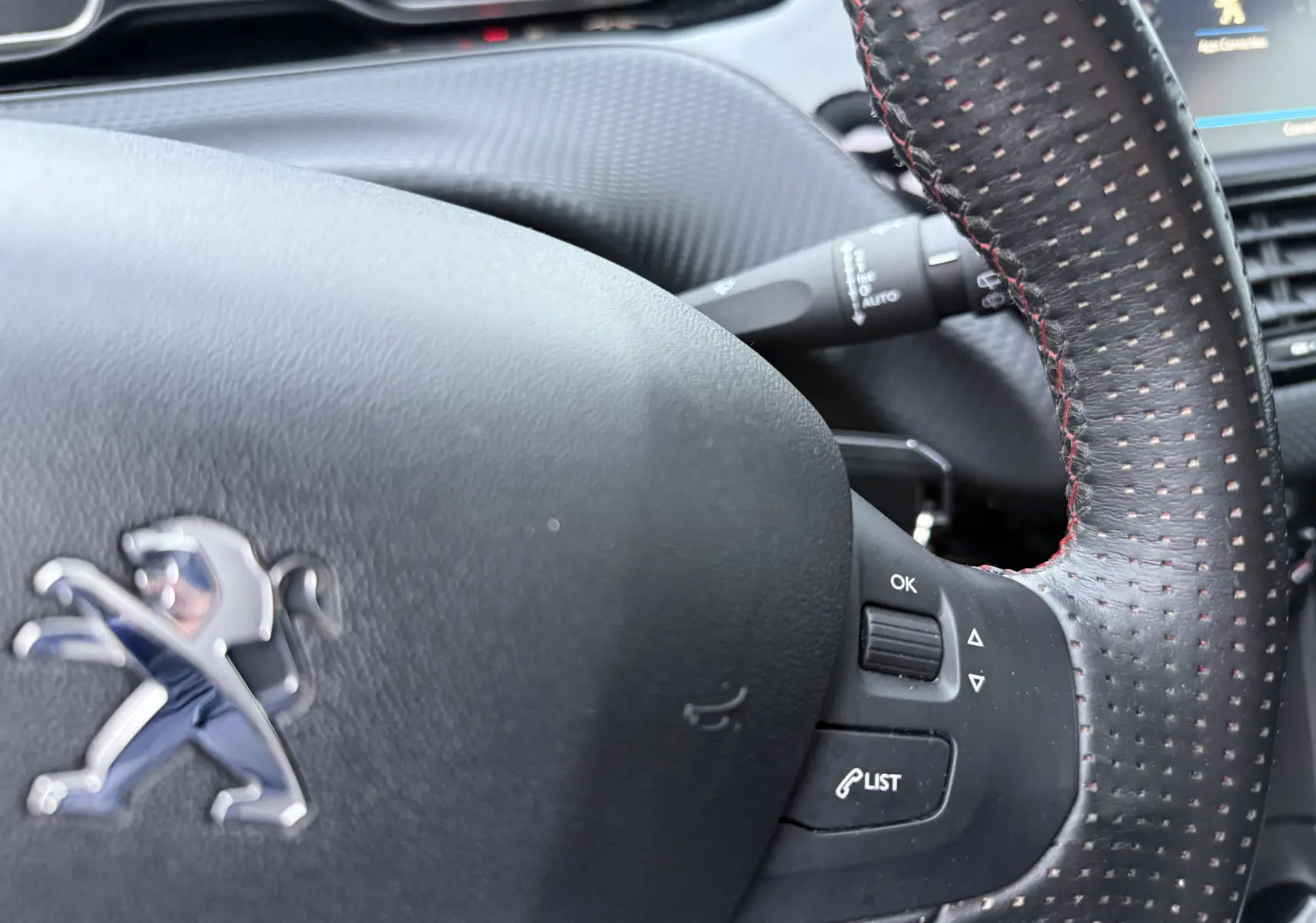 Gros plan sur le volant en cuir perforé avec surpiqûres rouges du Peugeot 2008 noir, version GT Line 2018.