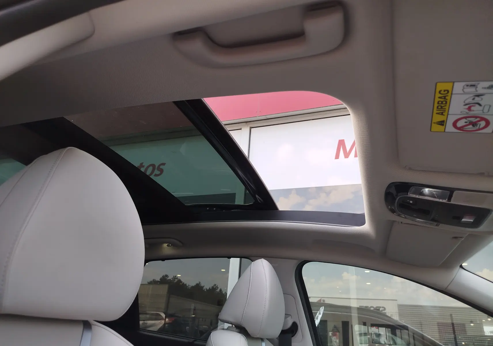 Vue intérieure du toit ouvrant panoramique du Hyundai Tucson 2021, sièges cuir blanc et ciel visible à travers le verre.