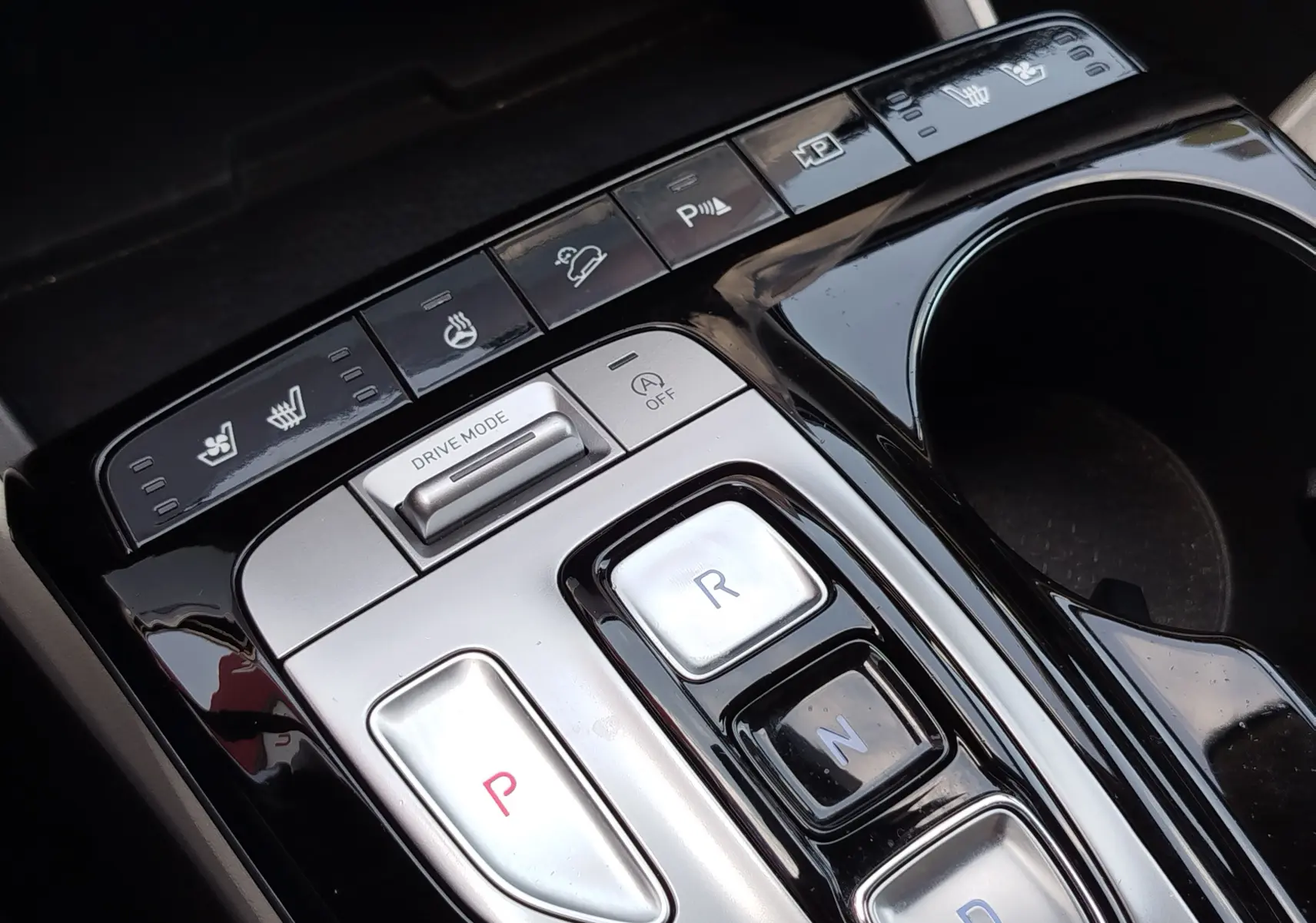 Gros plan sur la console centrale noire et argentée du Hyundai Tucson 2021, avec boutons de boîte auto et commandes de sièges chauffants.