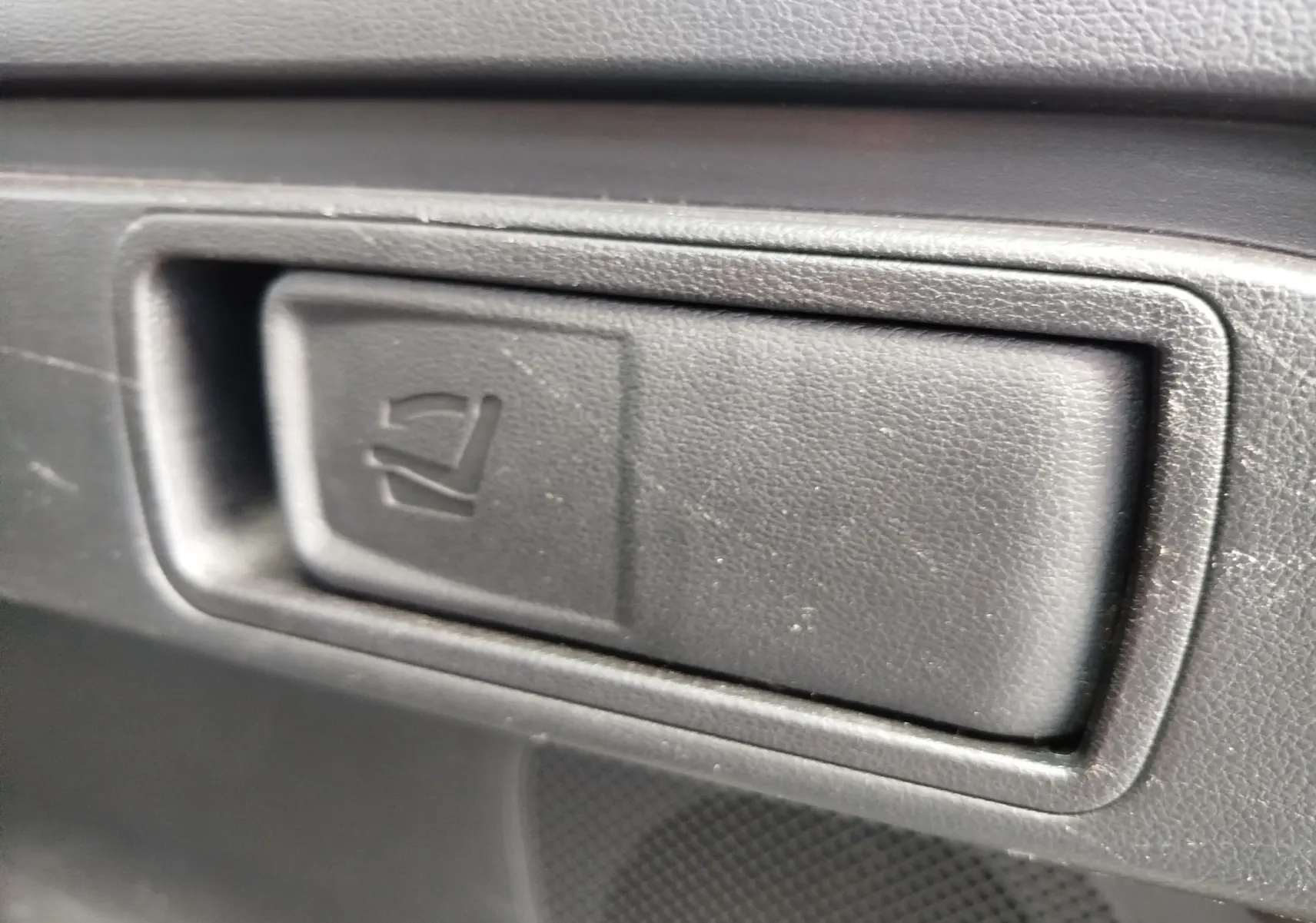 Gros plan sur le bouton de rabattement des sièges arrière en plastique noir à l'intérieur du Hyundai Tucson 2021 Teal Blue Métal.
